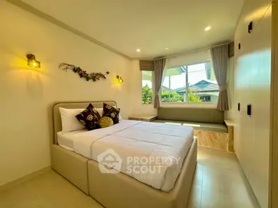 Bright and cozy bedroom with large window and modern decor in a serene residential area.
