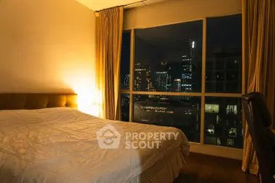 Luxurious bedroom with stunning city view at night, featuring elegant curtains and cozy lighting.
