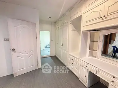 Spacious storage room with built-in cabinets and elegant white finish.