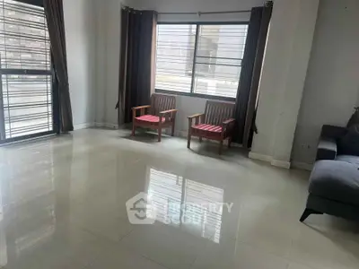 Spacious living room with large windows and modern furniture in a bright apartment.