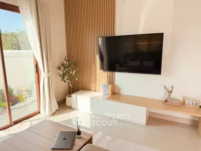 Modern living room with sleek TV setup and garden view, featuring elegant decor and natural light.