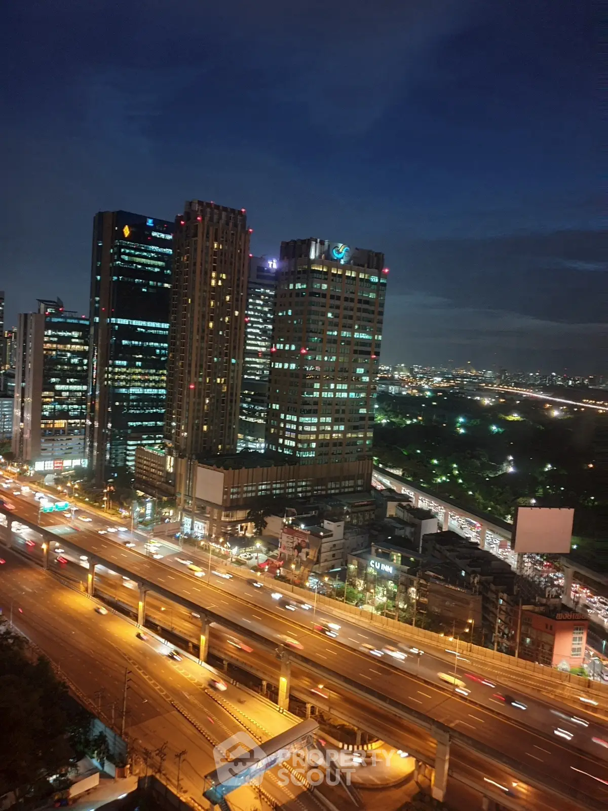 Stunning cityscape view from high-rise building at night with vibrant lights and bustling highway.