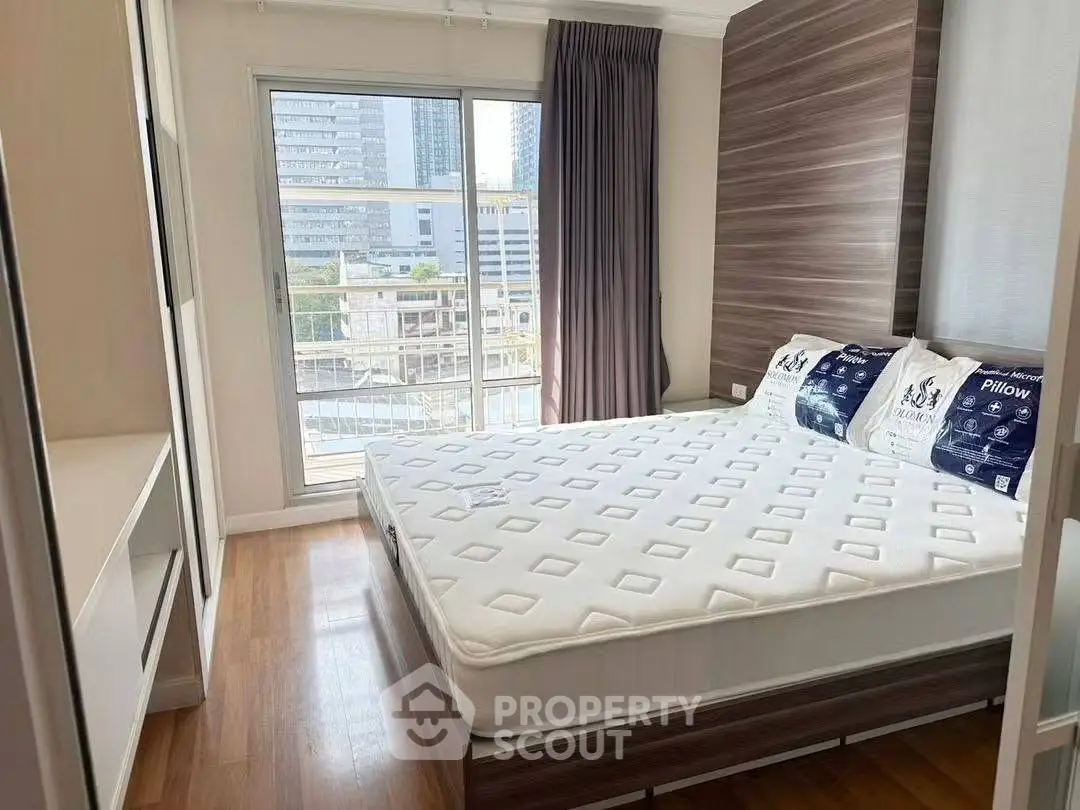 Bright and cozy bedroom with large window and modern decor in urban apartment.