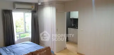 Cozy bedroom with built-in wardrobe and partial kitchen view in modern apartment