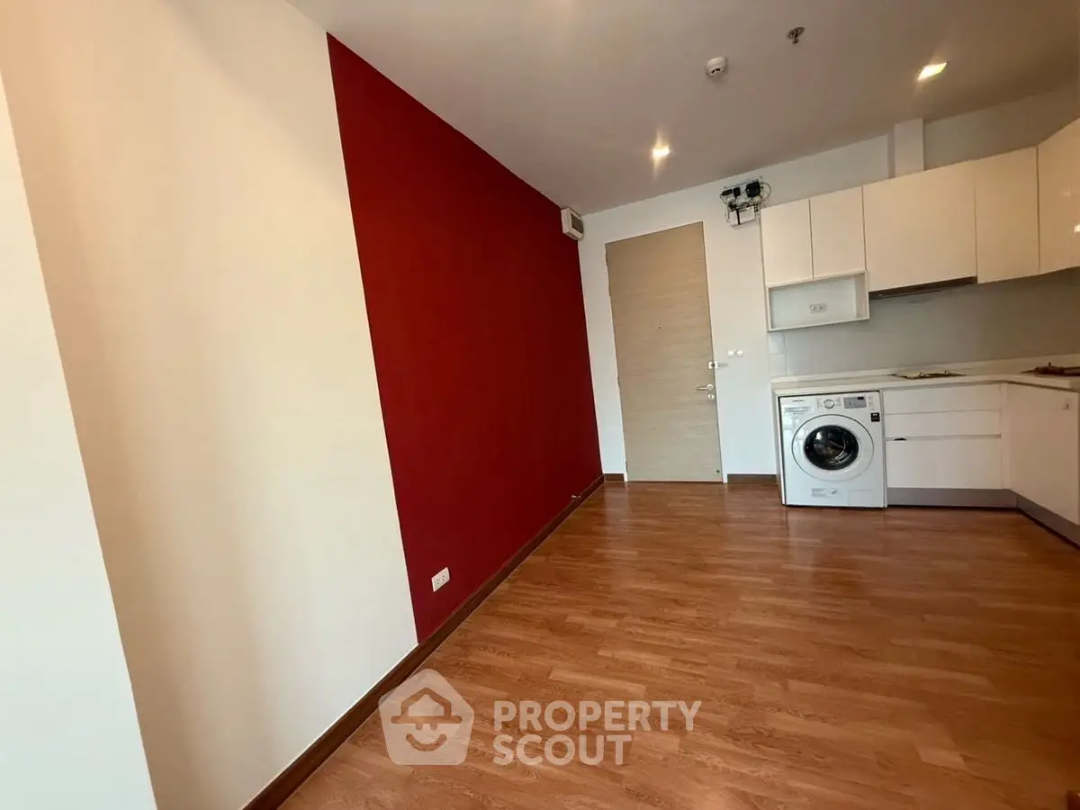 Modern apartment interior with red accent wall and washing machine in open kitchen layout.