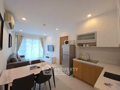 Modern open-layout living room and kitchen with sleek furniture and natural light.