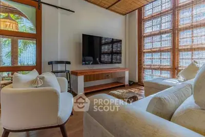 Charming living room with natural light, cozy seating, and modern TV setup.