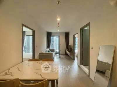 Modern open-concept apartment with living room and dining area, featuring large windows and stylish decor.