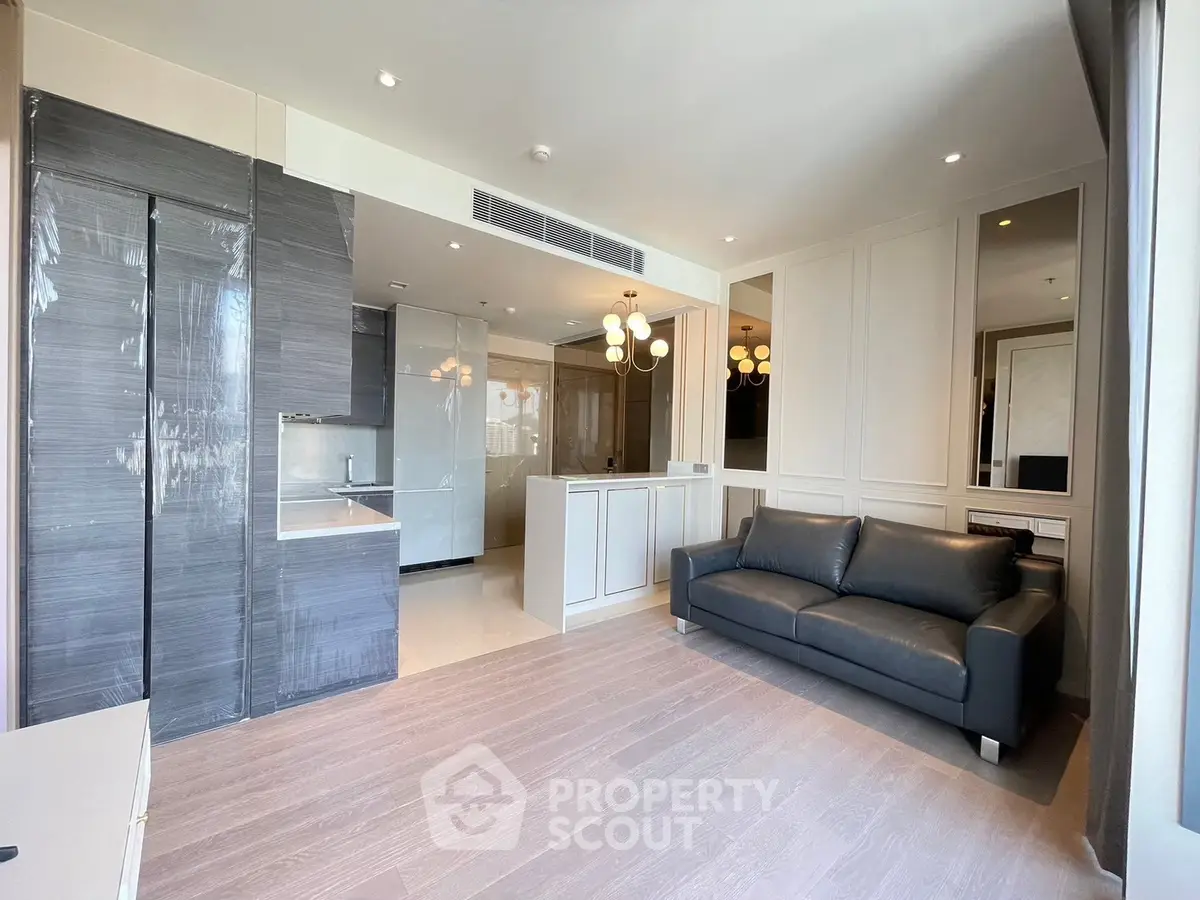 Modern living room with sleek kitchen and stylish lighting in open layout apartment.