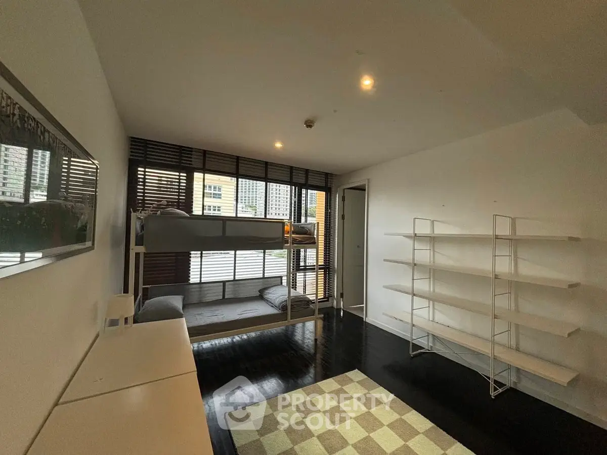 Spacious bedroom with bunk beds and modern shelving in urban apartment.