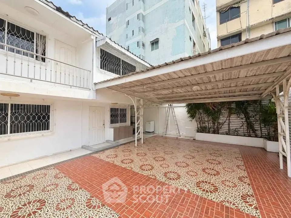 Spacious tiled courtyard with covered parking in urban residential area.
