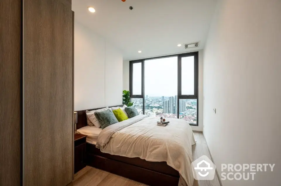 Modern bedroom with large windows and city view in high-rise apartment