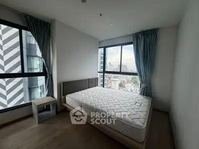 Modern bedroom with large windows offering stunning city views in a high-rise apartment.