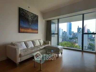 Modern living room with city view, featuring a sleek sofa and glass coffee table.