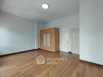 Spacious empty bedroom with wooden flooring and wardrobe