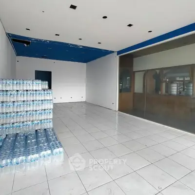 Spacious commercial space with tiled flooring and large glass window, ideal for retail or office use.