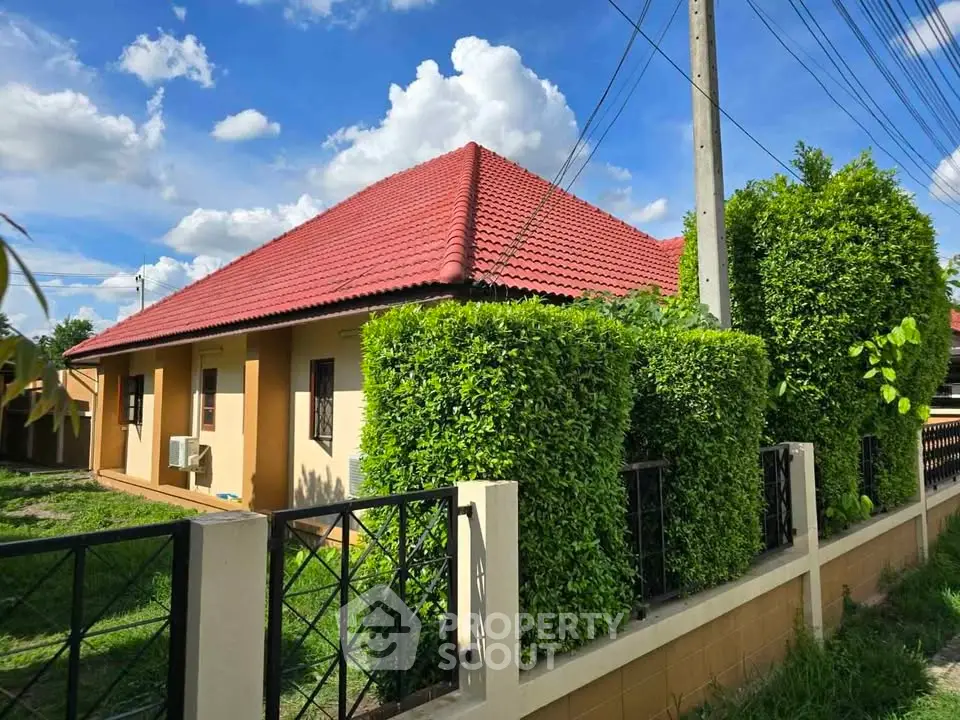 Charming single-story home with red-tiled roof and lush green hedges, perfect for serene living.