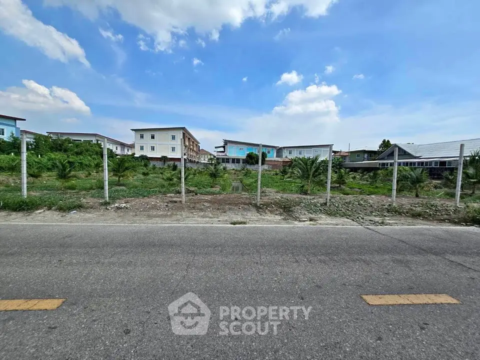 Expansive land plot with potential for development, surrounded by residential buildings under a clear blue sky.