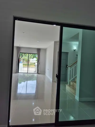 Spacious modern living room with glossy tiles and large windows offering natural light and garden view.