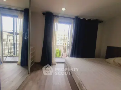 Spacious bedroom with large window and balcony access, featuring mirrored wardrobe and modern decor.