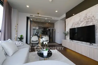 Modern living room with open kitchen, marble accent wall, and sleek decor