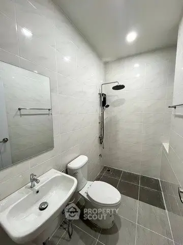 Modern bathroom with sleek fixtures and tiled walls, featuring a shower and toilet.