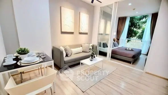 Modern open-plan living room with dining area and bedroom, featuring elegant decor and natural light.