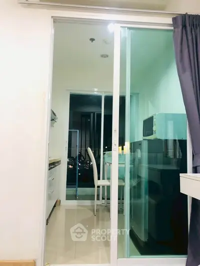 Modern kitchen with sliding glass door and sleek appliances in a stylish apartment.