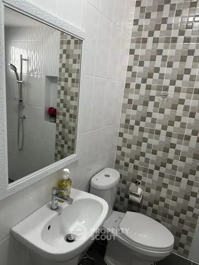 Modern bathroom with stylish tiles and sleek fixtures, featuring a shower and elegant mirror.
