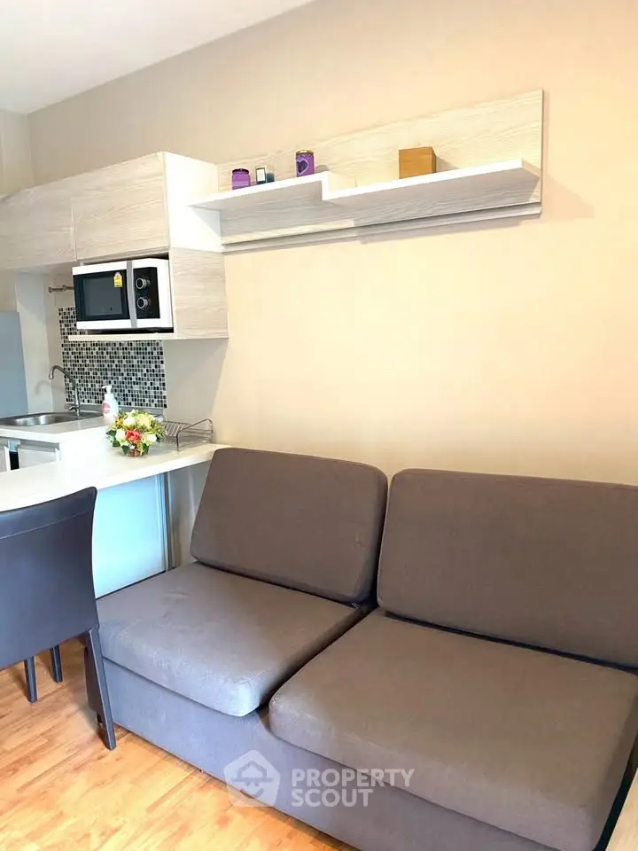 Modern living room with compact kitchen and cozy sofa in open layout apartment.