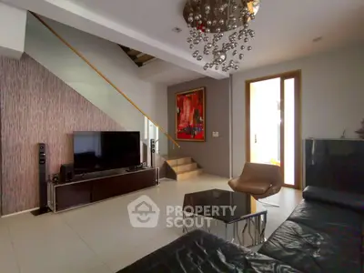 Modern living room with stylish decor and staircase, featuring a sleek TV setup and contemporary furniture.