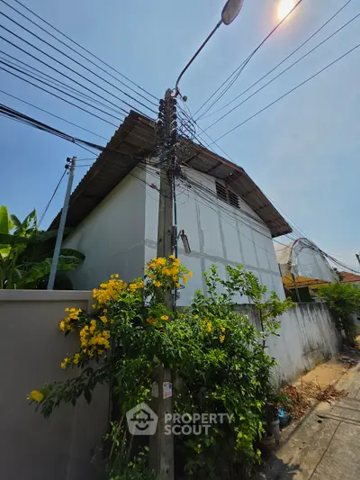 Charming residential exterior with lush greenery and vibrant flowers, showcasing a cozy urban home.