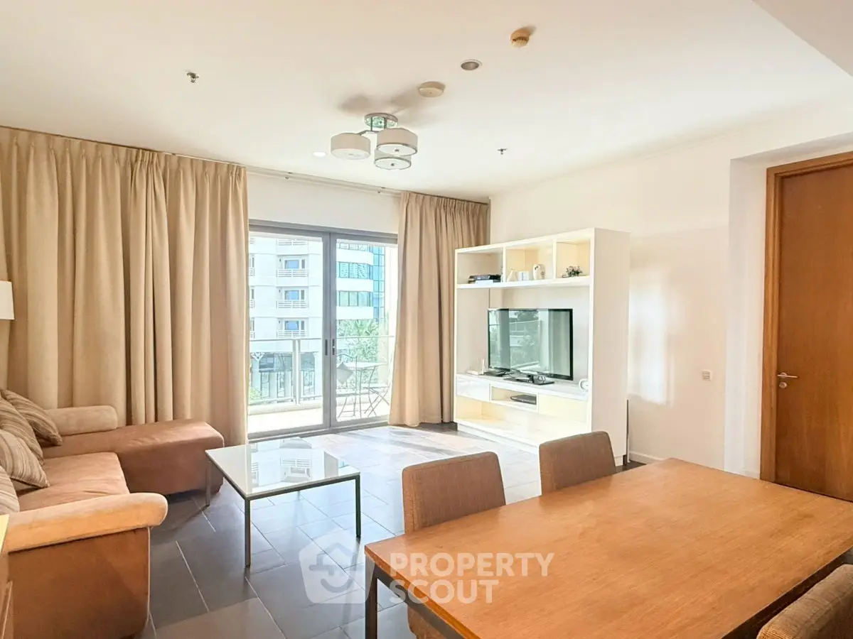Spacious living room with modern furniture and large windows offering natural light and city views.