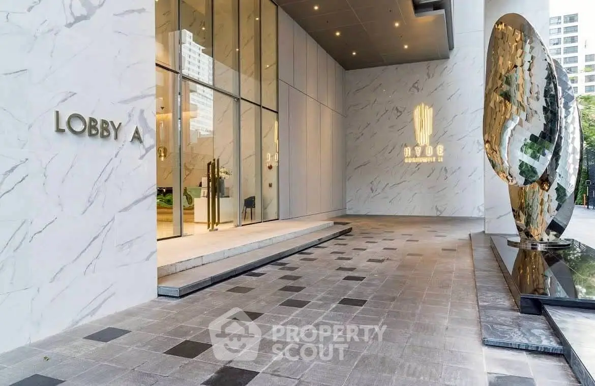 Luxurious building entrance with modern sculpture and elegant marble design.