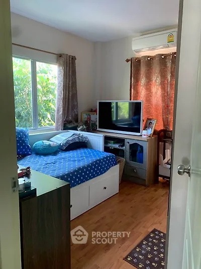 Cozy bedroom with natural light, featuring a comfortable bed, TV, and air conditioning, perfect for relaxation.