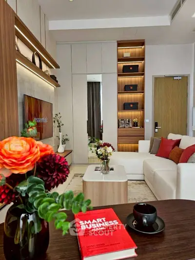 Modern living room with stylish decor and built-in shelving, featuring a cozy white sofa and vibrant flowers.