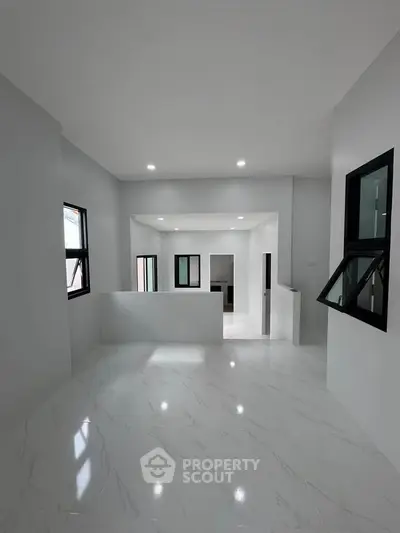 Spacious modern interior with sleek white flooring and large windows, perfect for natural light.