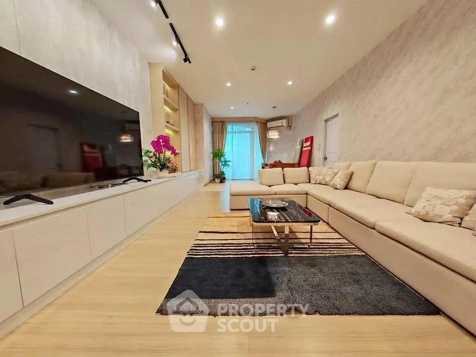 Spacious modern living room with large sectional sofa and sleek entertainment center.
