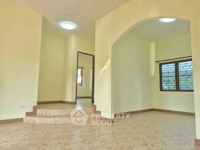 Spacious living room with unique tiled flooring and arched entryway, perfect for modern living.