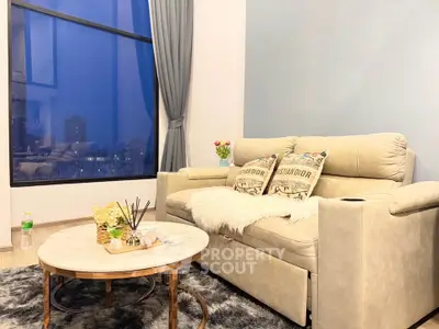 Stylish living room with large window and cozy seating area in modern apartment.