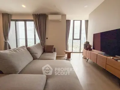 Modern living room with large windows and city view, featuring a cozy sectional sofa and sleek entertainment unit.