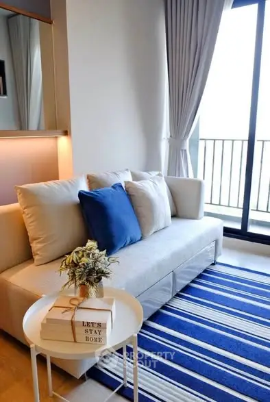 Cozy living room with modern sofa, striped rug, and balcony view in stylish apartment.