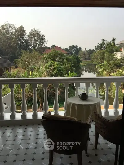 Charming balcony with serene garden and water view, perfect for relaxation and enjoying nature.