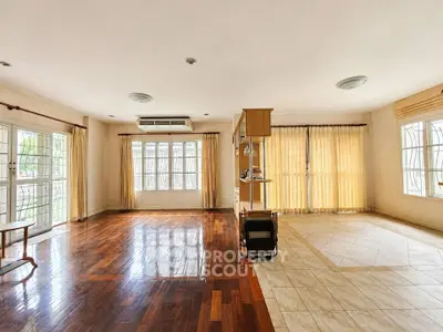 Spacious living room with wooden flooring and large windows for natural light.