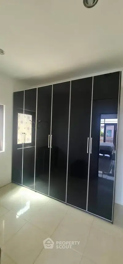Spacious bedroom with sleek black wardrobe and natural light