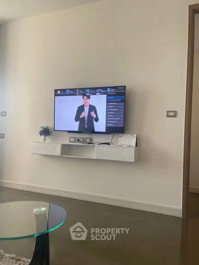 Modern living room with wall-mounted TV and sleek glass coffee table