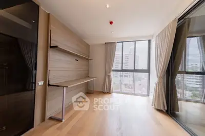 Spacious modern living room with large windows and wooden flooring in a high-rise apartment.