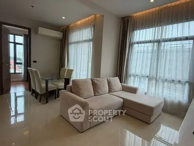 Spacious living room with modern furniture and large windows in a high-rise apartment.