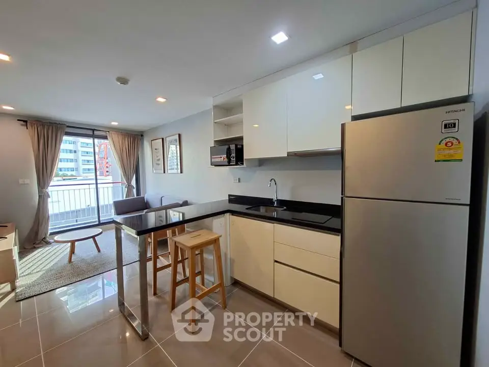 Modern open-layout kitchen with sleek appliances and bright living area in a stylish apartment.
