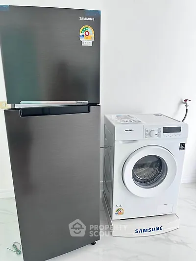 Modern kitchen appliances including a sleek fridge and washing machine in a bright interior.